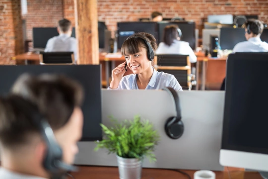 Frau mit Headset im Großraumbüro